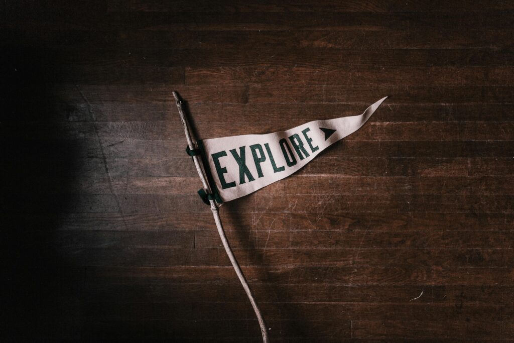 Artistic flat lay of an 'Explore' pennant on rustic wooden flooring, emphasizing adventure and exploration.